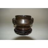 A Chinese twin handled bronze and inlaid censer, Qing dynasty, 12cm wide, on hardwood stand.