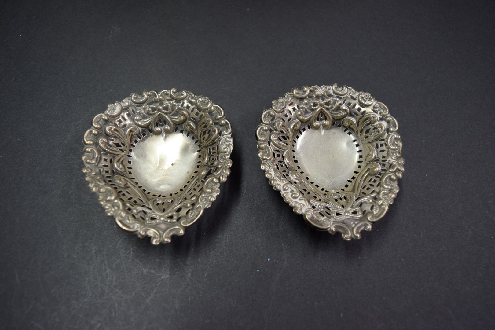 A pair of reticulated silver bonbon bowls; together with a pair of George III silver sugar tongs,