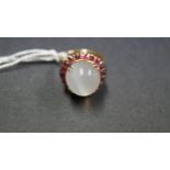 An 18k ring set large cabochon moonstone surrounded by garnets.