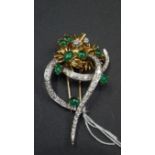 An ornate unmarked yellow and white metal brooch, set eight cabachon emeralds and pave set diamonds,