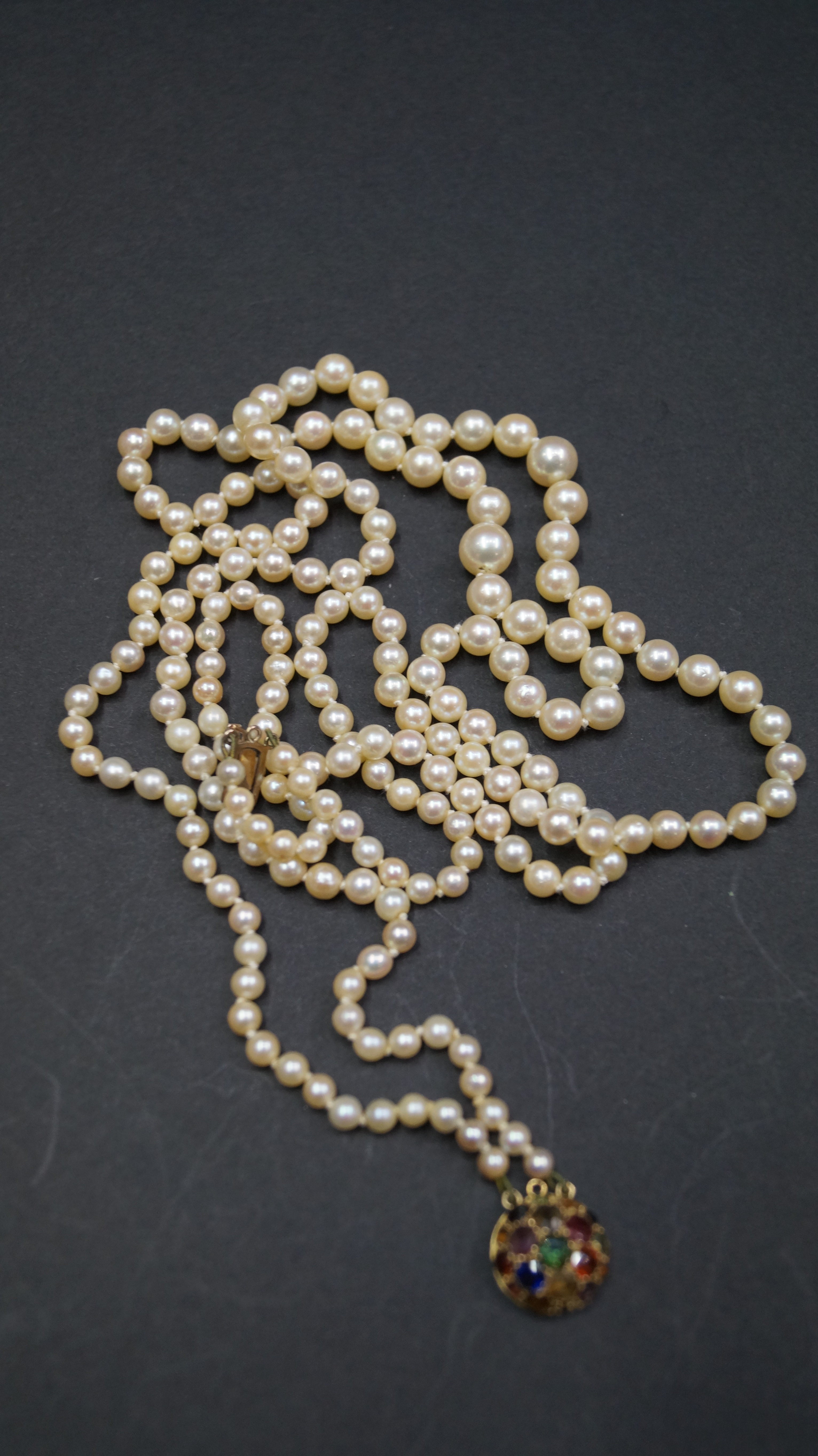 A single strand pearl necklace having yellow metal and gem set clasp,