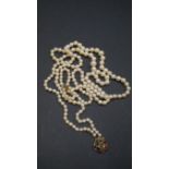 A single strand pearl necklace having yellow metal and gem set clasp,