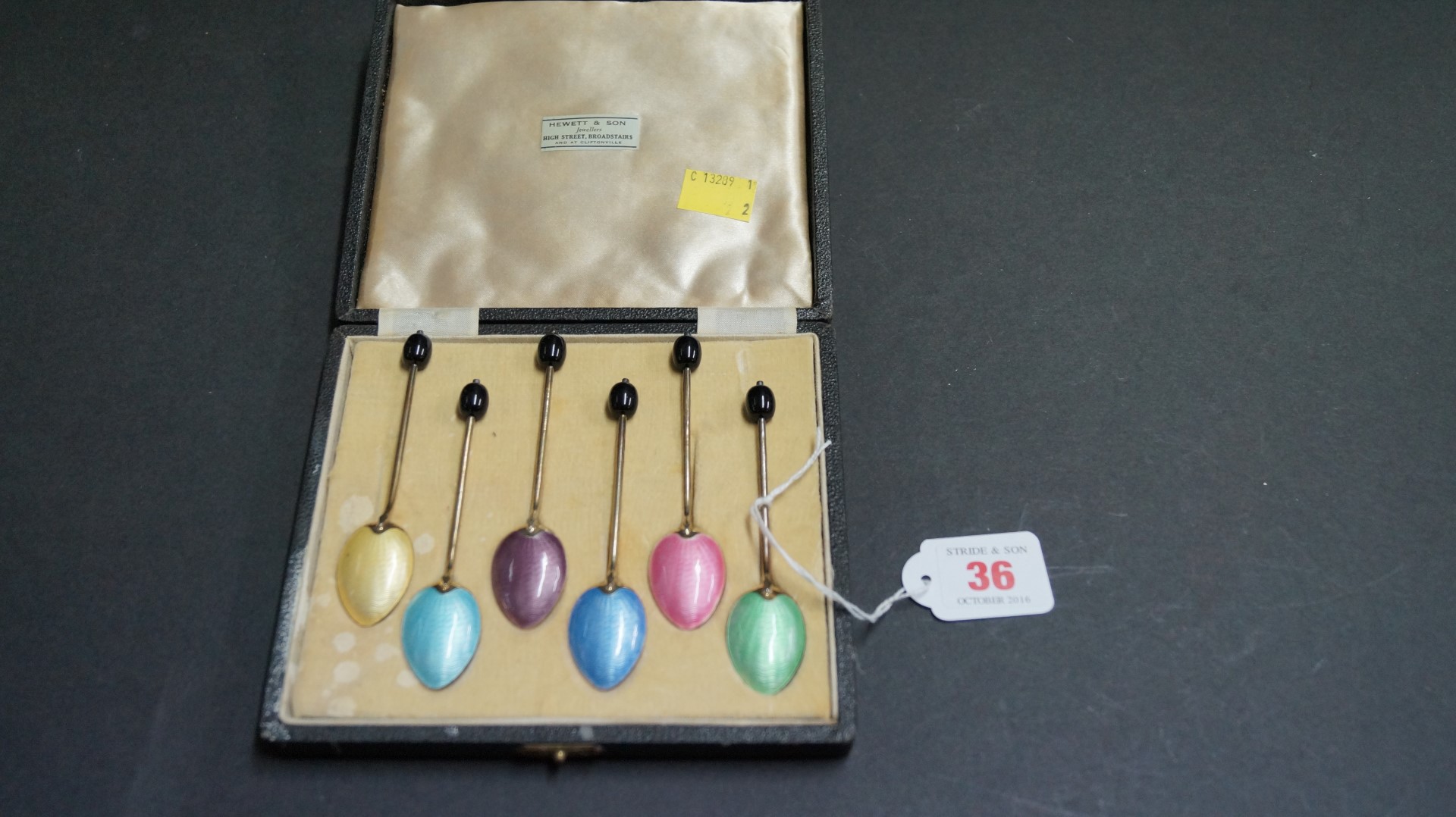 A cased set of six silver gilt and enamel coffee spoons having bean handles,