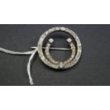 An unmarked pave diamond set circular horse shoe brooch. 2.8cm.