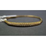 An 18ct yellow gold bangle bracelet set twenty one inline graduated brilliant cut diamonds,