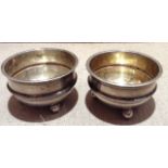 A PAIR OF EDWARDIAN HALLMARKED SILVER AND GILT CIRCULAR SALTS Resting on three ball feet, with