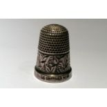 A HALLMARKED SILVER THIMBLE Having an engraved leaf design, with a hammered finish, Chester, 1904.