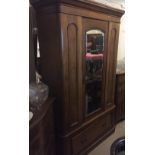 A VICTORIAN MAHOGANY WARDROBE With a single mirrored door above a drawer.