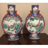 A PAIR OF 20TH CENTURY CHINESE MOON FLASKS Decorated with garden scenes, on a cream and blue ground.