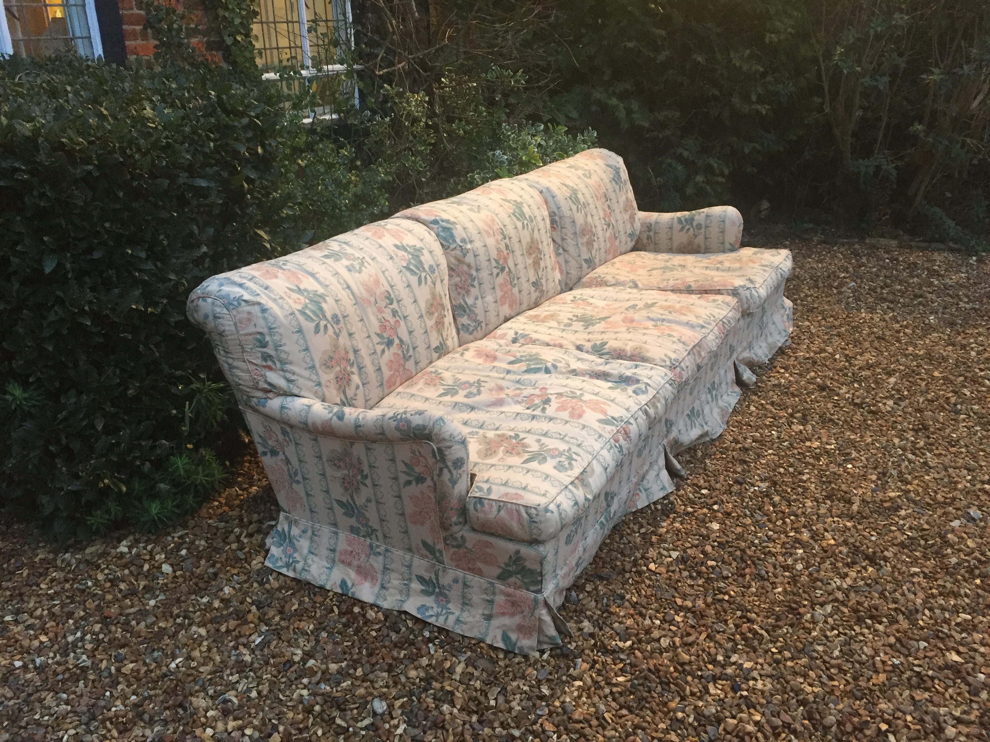 HOWARD CHAIRS LTD, A LARGE THREE SEATER SETTEE In later floral fabric upholstery, raised on six