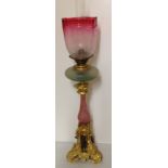 A VICTORIAN BRONZE ORMOLU AND CRANBERRY GLASS OIL LAMP Having an architectural style base, with