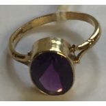 A HALLMARKED 9CT GOLD AND AMETHYST DRESS RING The oval cut amethyst collet set, to bifurcated