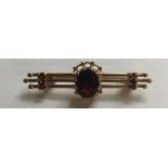 A HALLMARKED 9CT GOLD AND GARNET BROOCH The oval cut garnet claw set to a pierced and granulated