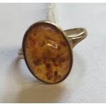 A 9CT GOLD AND AMBER DRESS RING The oval amber cabouchon collet set, to trifurcated shoulders (