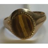 A HALLMARKED 9CT GOLD AND TIGERS EYE SIGNET RING The oval flat cut tigers eye bezel, in a serrated