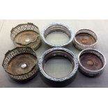 THREE PAIRS OF EARLY 20TH CENTURY SILVER PLATED WINE COASTERS To include two pairs with mahogany