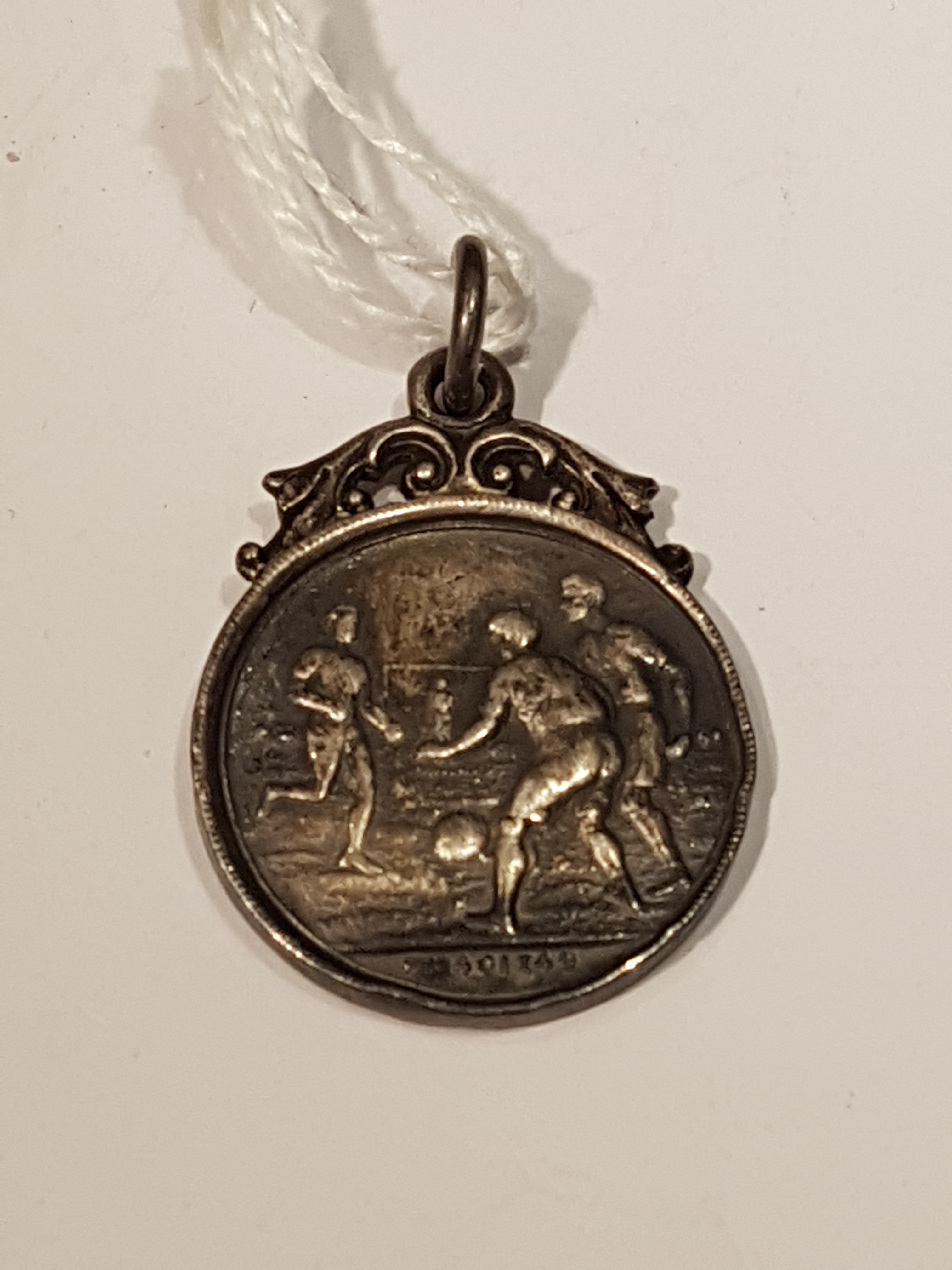 A 1920'S HALLMARKED SILVER FOOTBALL MEDAL With scrolling foliate surmount and football players to - Image 2 of 2