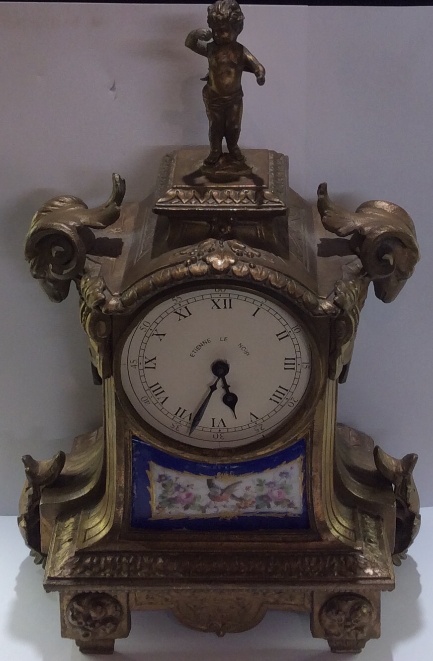 A 19TH CENTURY FRENCH SPELTER AND ORMOLU MANTEL CLOCK Cast with rams heads and a figural finial,