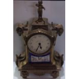 A 19TH CENTURY FRENCH SPELTER AND ORMOLU MANTEL CLOCK Cast with rams heads and a figural finial,