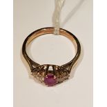 A 9CT GOLD, RUBY AND DIAMOND DRESS RING The oval faceted ruby claw set, between graduated pairs of