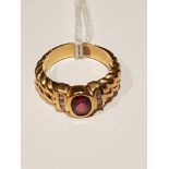 AN 18CT GOLD, GARNET AND DIAMOND DRESS RING The oval cut garnet collet set, between two vertical