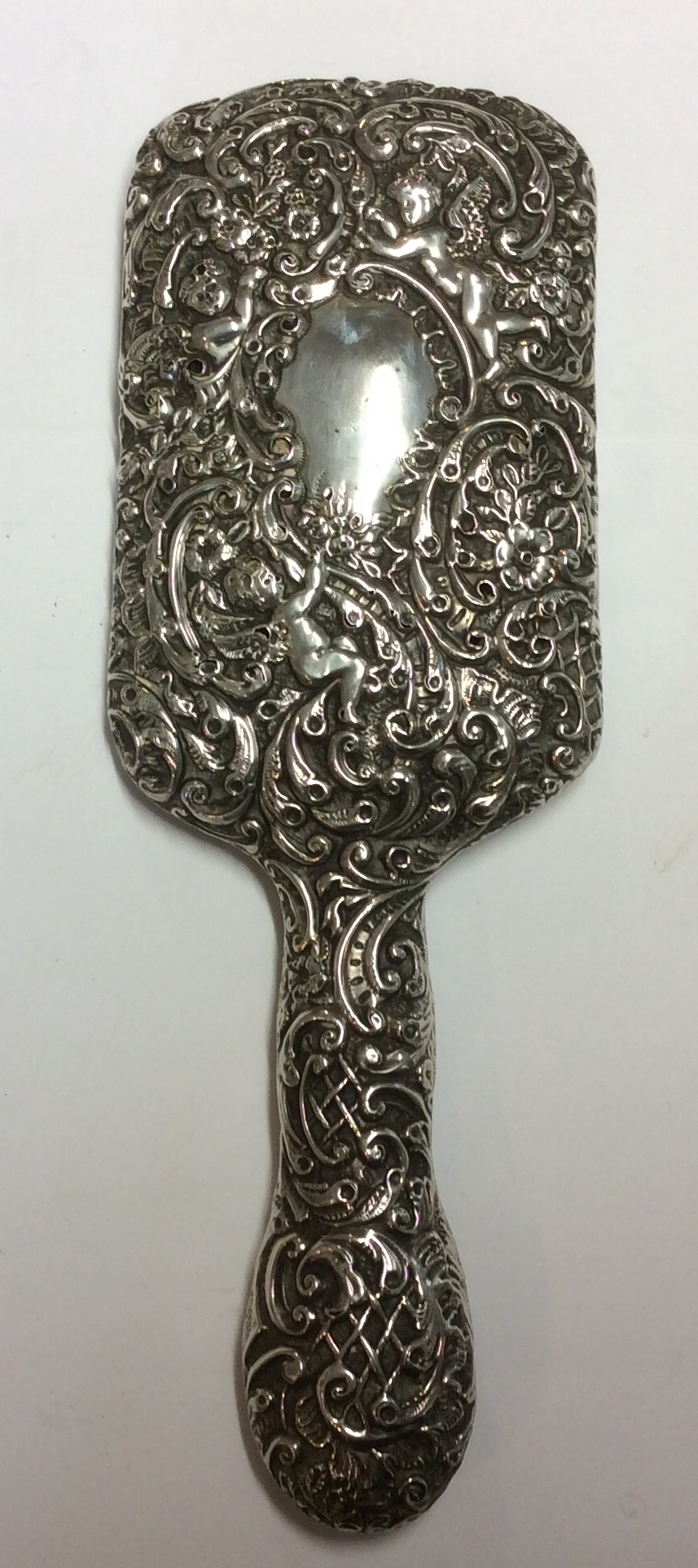 AN EARLY 20TH CENTURY HALLMARKED SILVER DRESSING HAND MIRROR Embossed with winged cherubs,