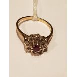 A HALLMARKED 9CT GOLD, RUBY AND DIAMOND FLOWERHEAD CLUSTER RING The round cut ruby claw set to a