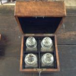 A LATE 19TH/EARLY 20TH CENTURY OAK CASED AND CUT GLASS DECANTER BOX Holding four square cut bottles,