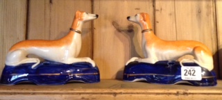 A PAIR OF 19TH CENTURY STAFFORDSHIRE POTTERY SPILL VASES Modelled as recumbent dogs, with light