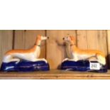 A PAIR OF 19TH CENTURY STAFFORDSHIRE POTTERY SPILL VASES Modelled as recumbent dogs, with light