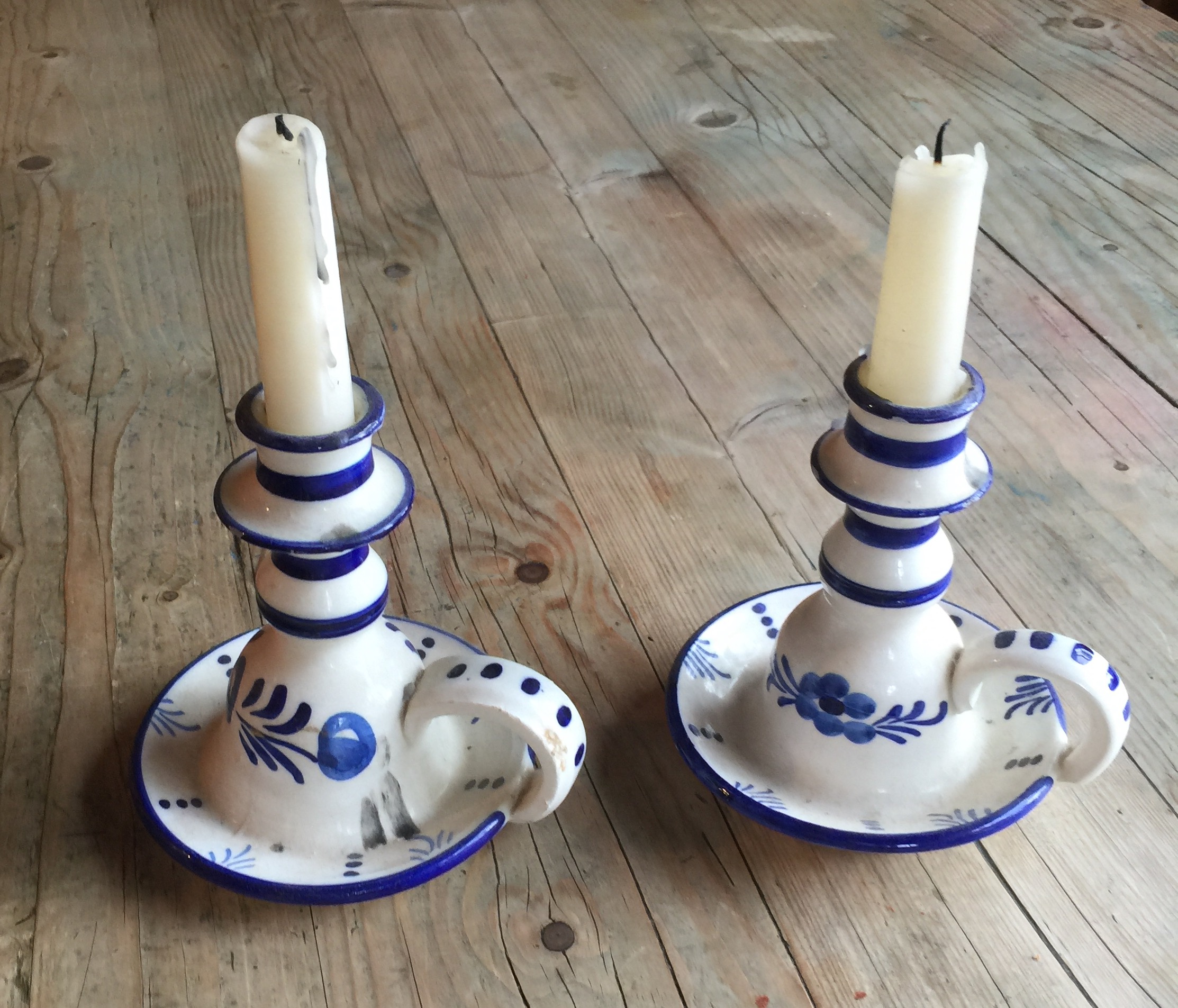 A PAIR OF DELFTWARE BLUE AND WHITE CHAMBERSTICKS Painted with flowers, having a single carry