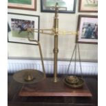 A LARGE SET OF BRASS SCALES AND WEIGHTS On a mahogany base.