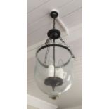 A GLASS AND BRASS LANTERN Having a dome shaped glass shade and chain suspension.