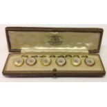 A CASED SET OF SIX EDWARDIAN 18CT GOLD AND MOTHER OF PEARL BUTTONS The round gold mounted buttons,