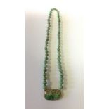 A NECKLACE OF GRADUATED SPHERICAL JADE BEADS Suspending an antique carved jade plaque, in 14ct