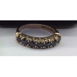 A LATE 20TH CENTURY 9CT GOLD AND SAPPHIRE HALF ETERNITY RING The seven round cut sapphires claw set,