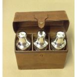 AN EARLY 20TH CENTURY HALLMARKED SILVER SET OF THREE CASED PERFUME BOTTLES In a pigskin leather
