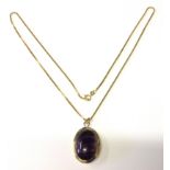 AN 18CT GOLD AND SYNTHETIC AMETHYST PENDANT AND 9CT GOLD CHAIN The oval cabouchon synthetic