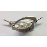 A VINTAGE SILVER AND CULTURED PEARL BROOCH The two white pearls prong set to a curved bar, decorated
