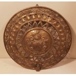 A 19TH CENTURY CIRCULAR BRASS SHIELD REFLECTOR PLATE With repoussé decoration, a coat of arms, along