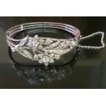 AN EDWARDIAN STYLE 18CT WHITE GOLD AND DIAMOND BANGLE The hinged triple banded bangle, widens at the