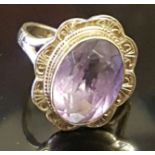 A HALLMARKED 9CT GOLD AND AMETHYST DRESS RING The oval cut amethyst collet set, to a scalloped