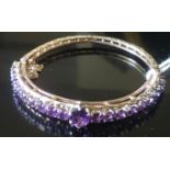 A VICTORIAN STYLE 9CT GOLD AND AMETHYST BANGLE The hinged bangle claw set to front, with an oval cut