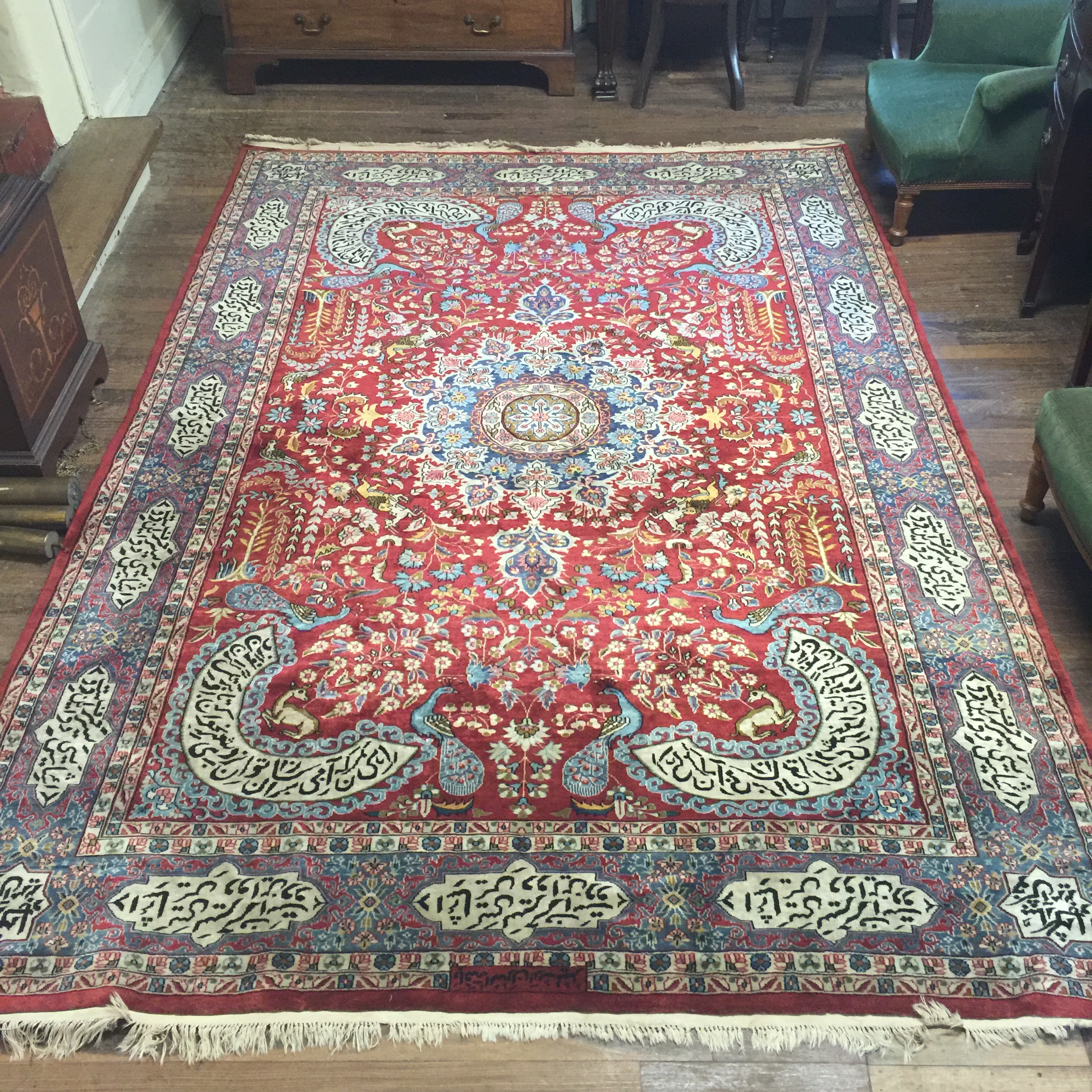 A PERSIAN RUG With central madder field and numerous script, contained within running borders. (
