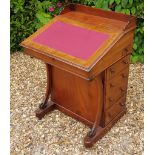 A VICTORIAN MAHOGANY DAVENPORT DESK With a gallery back above a red leatherette slope, opening to