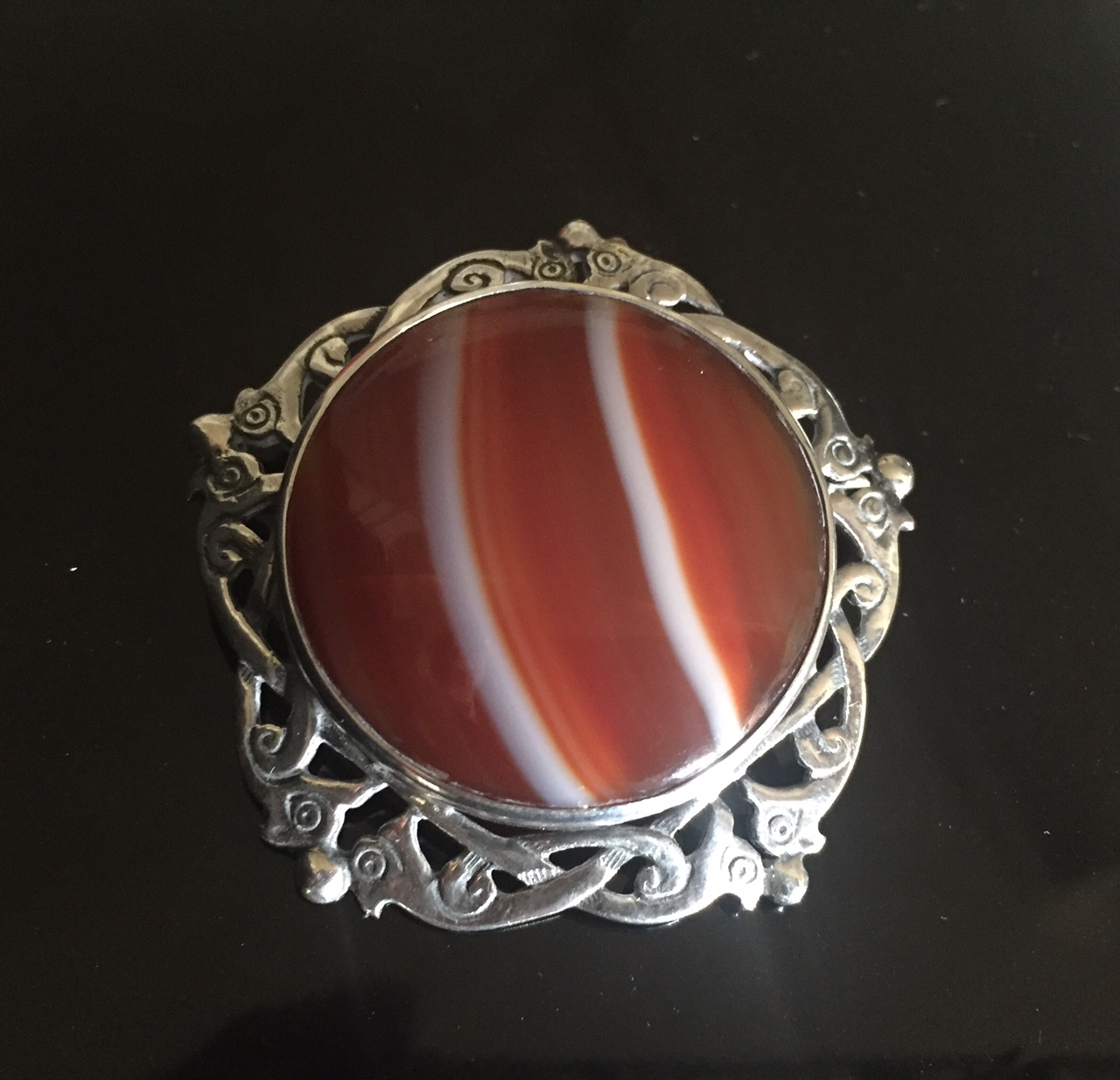 A SCOTTISH SILVER AND AGATE BROOCH FROM JONA The circular polished agate plaque collet set to an