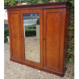 A VICTORIAN MAHOGANY TRIPLE WARDROBE The arched panelled doors enclosing a fitted interior, linen