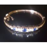 A VICTORIAN STYLE 14CT GOLD, SAPPHIRE AND DIAMOND BANGLE Set to front with three cushion cut