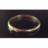 A HEAVY 9CT GOLD BANGLE The solid hinged 'D' section bangle, having a box clasp and safety chain (