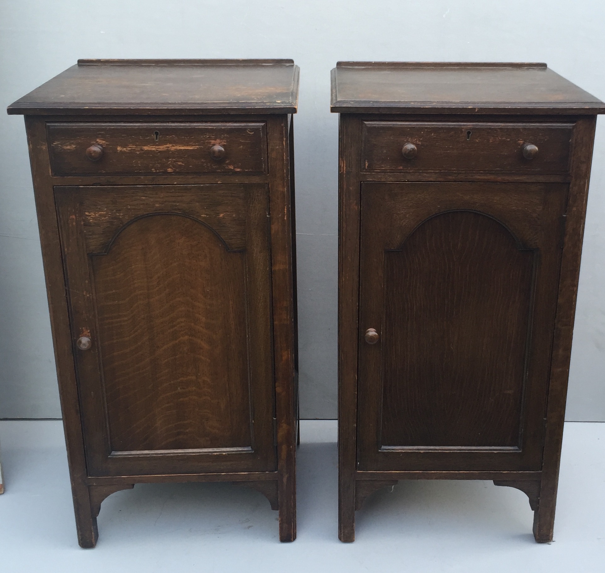 TWO EARLY 20TH CENTURY OAK BEDSIDE CABINETS With single drawers above arched panelled doors.